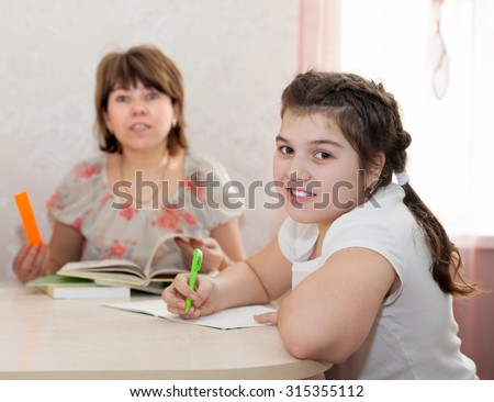 Adult woman helping   to   teenager to learn   lessons at home.