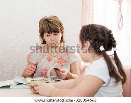 Adult woman helping   to   teenager to learn   lessons at home.