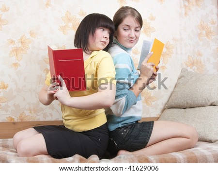 Two joy girls with books sitting on sofa