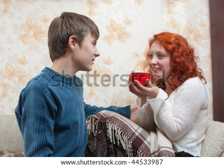 Mother is sicking and her son giving a cup of tea