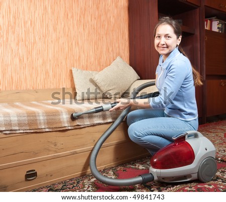 Photo of an attractive senior woman vacuuming her living room.