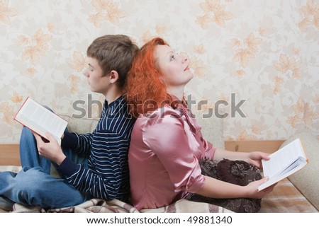 Mom and her son sitting on sofa and reading books