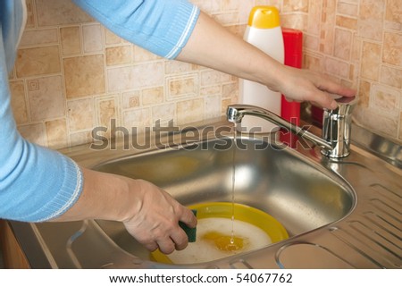 Woman washing dirty dishes in the kitchen sink