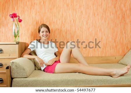 stock photo Pretty teen girl in shorts sitting on sofa at home