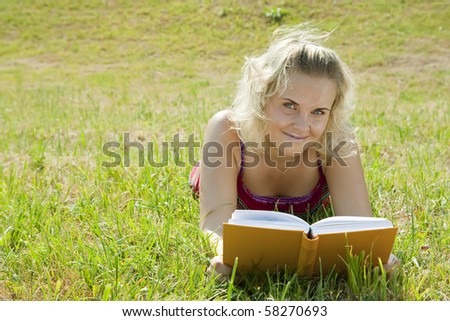 Young reading woman lying in grass during sunny day