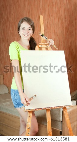 Young painter near easel in living room