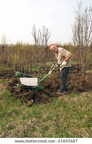 Senior gardener  working in the yard with mini tractor