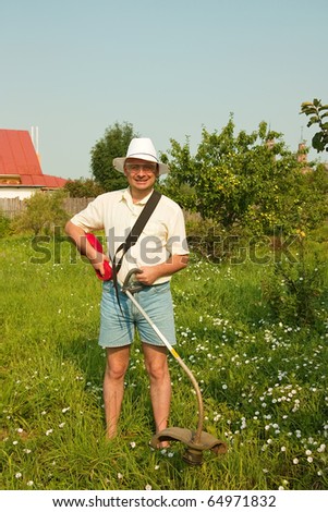 Adult gardener is fixing lawn trimmer  in garden