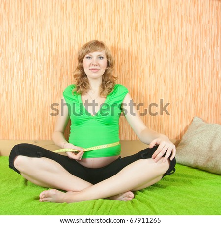 Happy pregnant woman measuring belly  at home