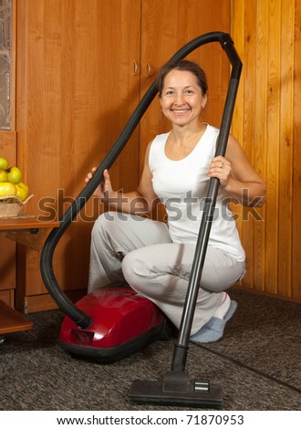 Photo of an attractive senior woman vacuuming her living room.