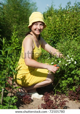 Mature, middle-aged woman plants flowers in garden