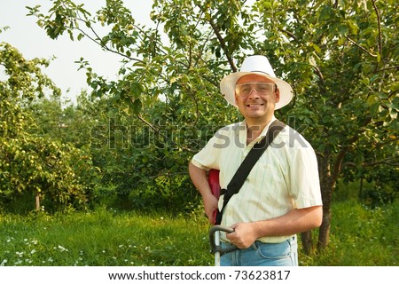 A man works with cordless grass trimmer in garden