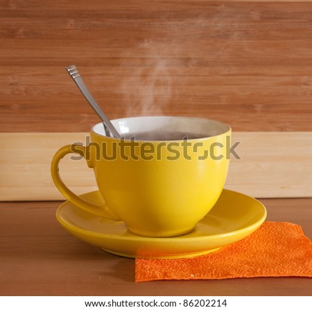 Cup of hot tea with steam on wooden background. Light tone.