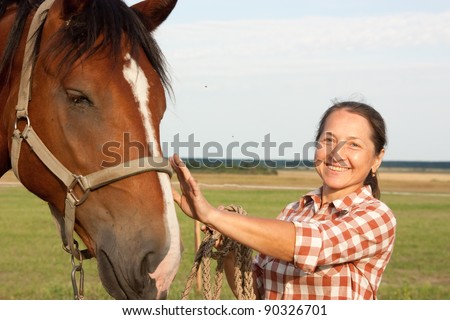 Mature woman walking with her horse in rural areas