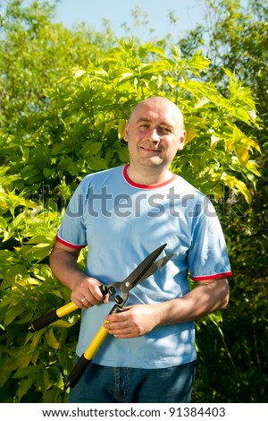 Mature man with garden pruner near   bush