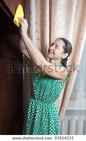 Matuure woman cleaning furniture  cabinet  with yellow duster