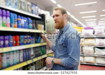 Man near  department with  tools for body care in   supermarket  \shaving products
