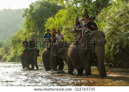 KANCHANABURI/THAILAND - MAY 2015 - while tourists Sitting on an elephant\'s back overlooking the river. MAY, 9, 2015 in Kanchanaburi, Thailand.