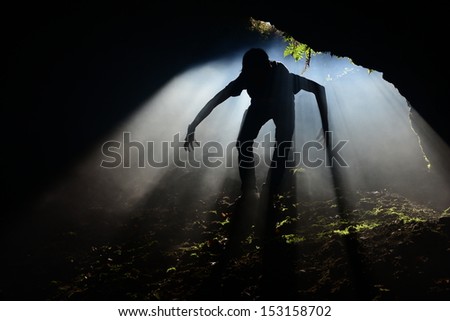 A silhouette of a person inside a mine entrance with sunlight protruding.