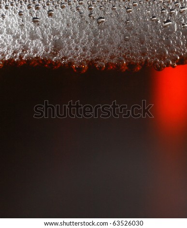 Macro shot of dark beer with froth.