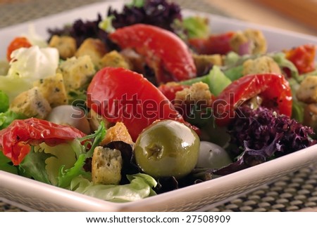 Close up of a salad platter with olives, dried tomatoes, mozarella & croutons