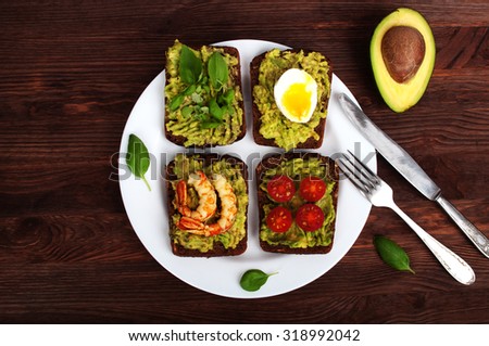 Sandwiches with avocado puree; avocado oil; bread; delicious cold snacks; vegetarian meals; healthy eating; organic food; green oil; sandwiches on a white plate; avocado; shrimp; egg; basil