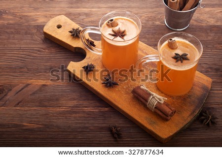 Apple cider in glass cups on a dark wooden background; cinnamon; star anise; the concept of home-made cider