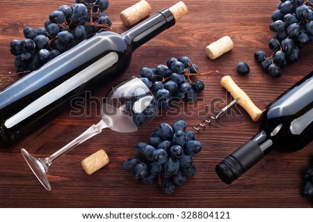 Wine in the bottles and wine in the glass on a dark background; grapes; corkscrew; corks; the substrate for the wine list; drinking wine