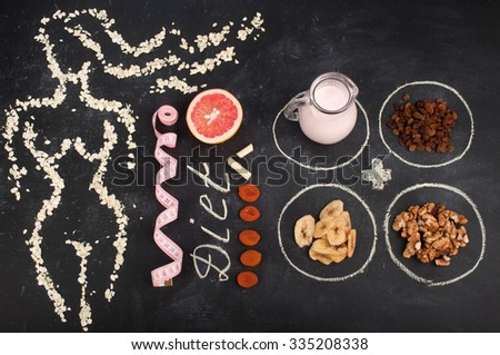 The concept of diet food. The figure of a woman\'s body lined with oat flakes on a dark background, near grapefruit, yogurt in a jar, walnuts, raisins, banana chips
