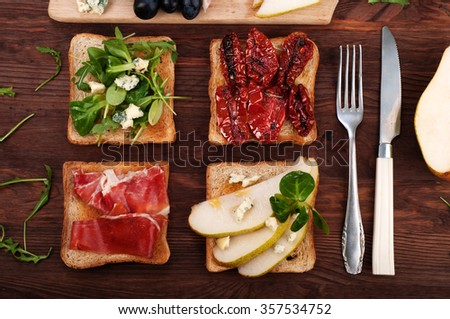 Sandwiches with different toppings, near knife and fork. The concept of home-cooked gourmet sandwiches