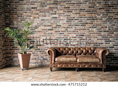 Interior mock up photo. Brownish brick wall with leather sofa and pot with plant. Background photo with copy space for text.