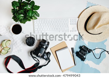 Beautiful hipster flatlay with hat, dslr camera, lens, coffee, map, flower, notebook and binocular. Working space surface top view. Creative work table for photographer, traveller, blogger