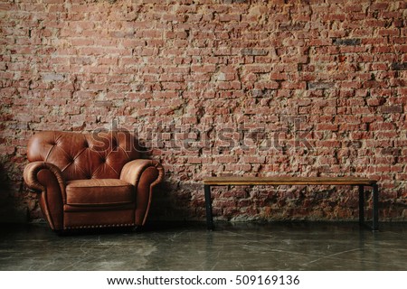 Loft interior mock up photo. Brown red brick wall with leather sofa and minimalist wooden table. Background photo with copy space for text. Horizontal