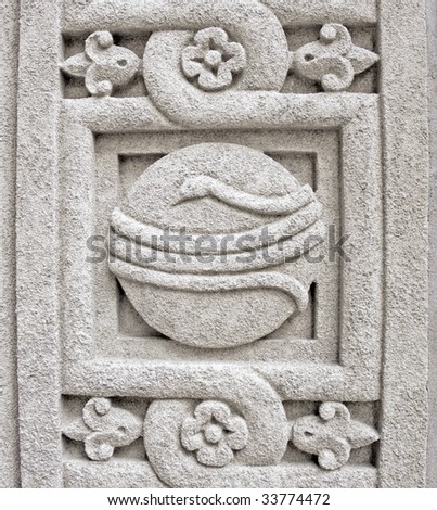 Circular design with a snake and flowers carved into old stone