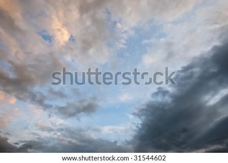 Ominous storm clouds with sunset orange cast on layer above gray rain clouds