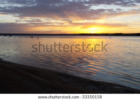 Beach and coastline visible with yellow sun and pastel shades of clouds in sky