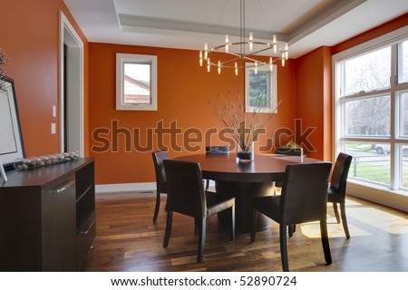 Luxury Dining Room with Orange Walls. Brightly lit with large windows.