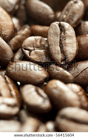 Extreme close up of coffee bean in heap. Focus on upper right bean. Shallow depth of field and selective focus.