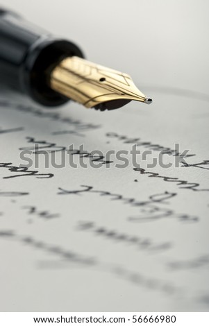 Gold pen with hand written letter. Focus on end tip of fountain pen.