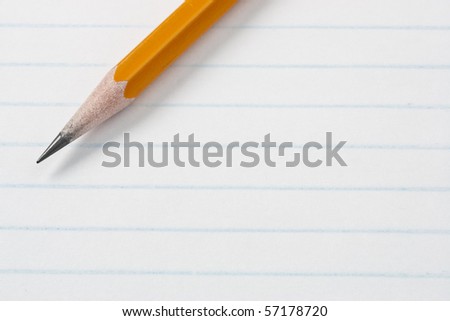 Pencil across lined note pad paper. Focus on tip of pencil.