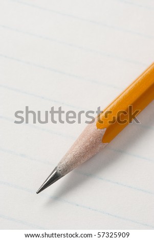 Pencil across lined note pad paper. Focus on tip of pencil.