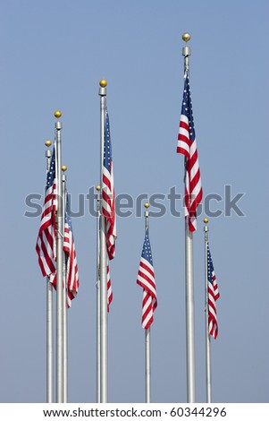 American Flags against blue sky in vertical orientation. Focus on middle front flag.