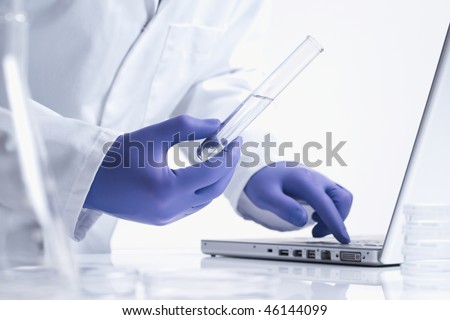 scientist entering data on laptop computer with test tube white background