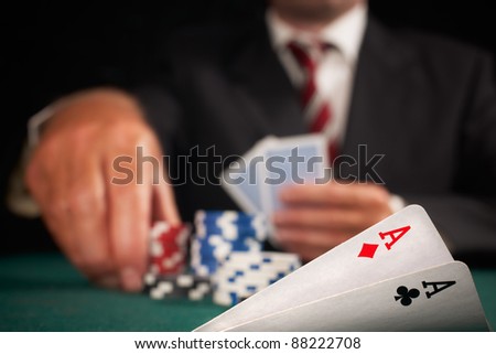 pair of aces and poker player gambling casino chips on green felt background selective focus