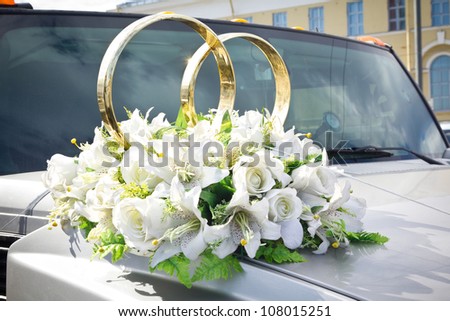 White wedding limousine decorated with flowers and gold rings