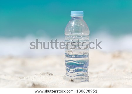 Water in bottle on sand on tropical beach