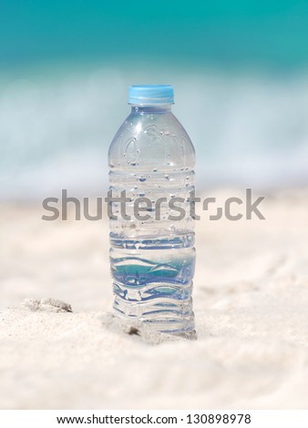 Drinking water in bottle on sand on tropical beach