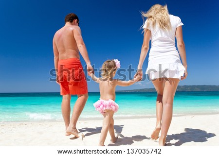 Mother, father and daughter having fun on tropical white beach