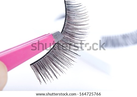 False lashes and pink pincers, closeup on white background