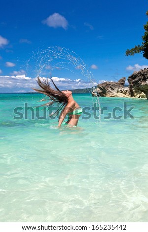 Woman in tropical sea waving hair and splashing out a water